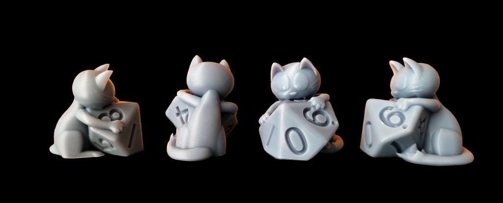 figurine 3D inédite en résine, de 30 mm de haut, reprséentant un chat en train de croquer un dé 10, réalisée spécialement pour le 10e festival du jeu de société de Valence, figurine d'après un dessin d'Arnü West